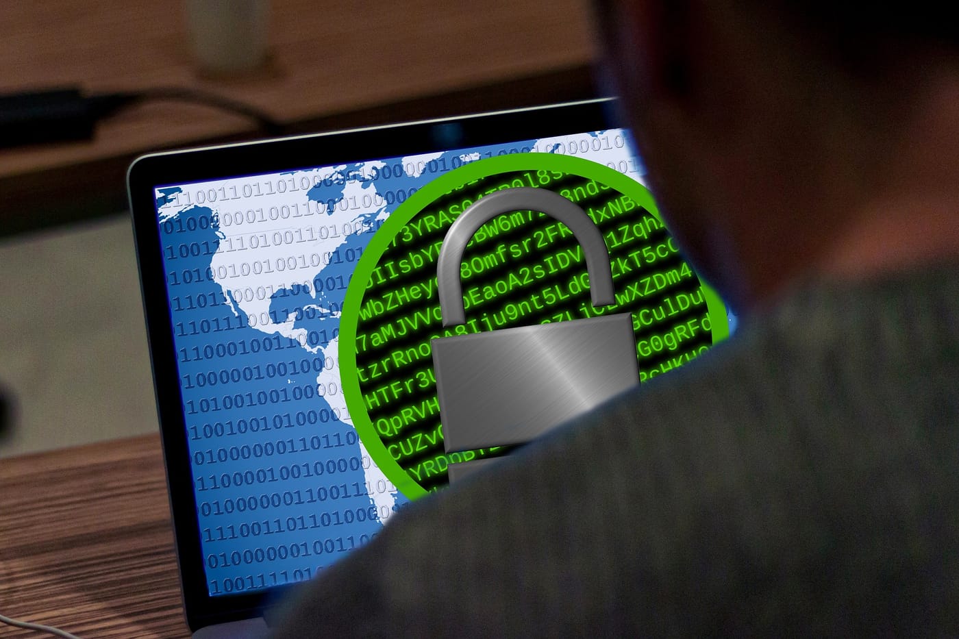 this photo shows a computer screen with a lock and a hacker sitting behind